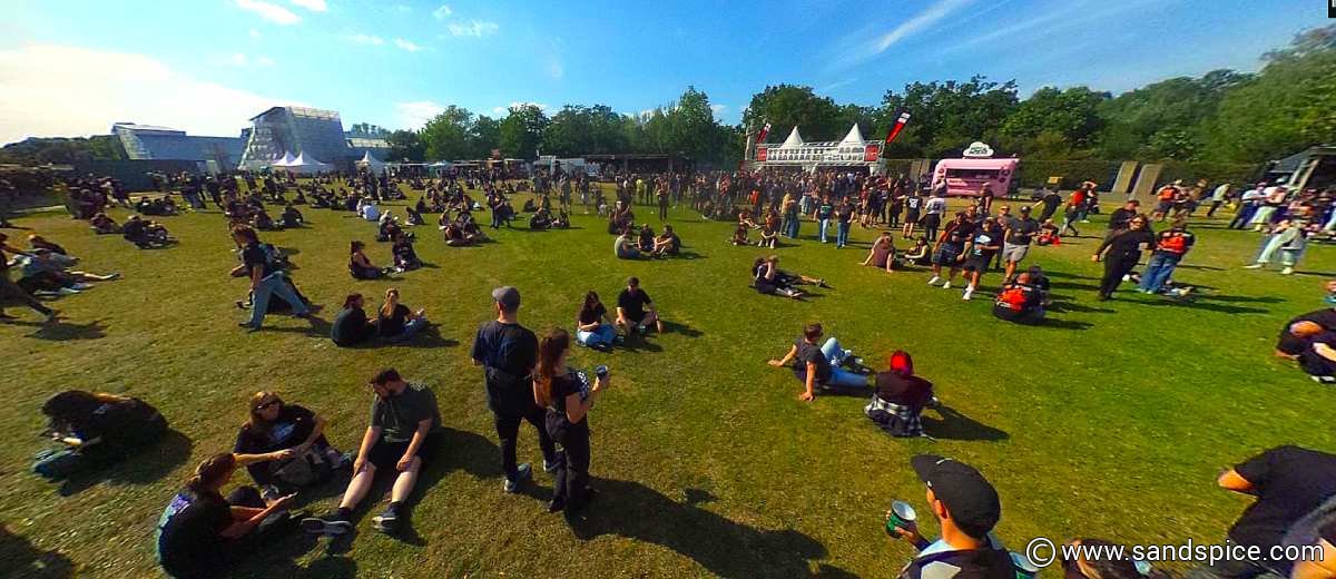Fans relaxing on the grass at an outdoor System of a Down festival area near the Berlin Olympiastadion before a concert.